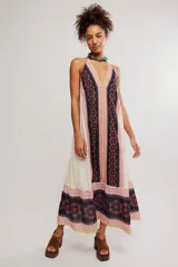 Vestido largo de tela liviana con estampado tipo patchwork de guardas florales en tonos negros, blancos y rosados, con escote en V profundo, tiras finas para anudar al cuello estilo halter y espalda descubierta.