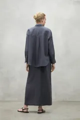 Camisa de corte holgado confeccionada en lino, con cuello clásico, cierre frontal de botones y mangas largas con puños sencillos.