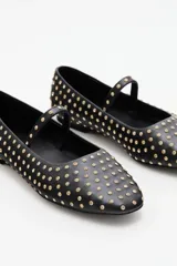 Balerinas negras con punta cuadrada, decoradas con múltiples studs dorados y una tira fina con hebilla sobre el empeine.