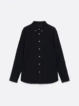 Camisa de sarga de puro algodón teñido en prenda, color azul marino, con cuello abotonado, bolsillo de parche en el pecho, puños redondeados con botón, cinta distintiva en el interior del cuello y logo de Tommy Hilfiger bordado en el bolsillo del pecho.