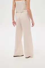Pantalón ancho de viscosa color beige claro, de tiro alto con cintura elastizada y cordón ajustable. Presenta bolsillos laterales decorados con detalles bordados geométricos.