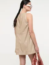 Vestido corto de eco cuero color beige, sin mangas, con escote en V y pespuntes a contratono.