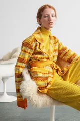 Saco largo medio con abertura frontal, bolsillos delanteros y cinto para ajustar. Presenta un diseño tejido con patrón geométrico en tonos amarillo, marrón y lila.