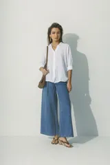 Camisa blanca de lino con cuello clásico, manga larga con puños abotonados y cierre frontal con botones. Corte recto y holgado.