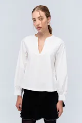 Blusa blanca de algodón con escote en V y mangas largas abullonadas.