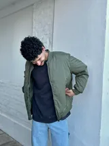 Campera bomber verde militar de nylon con cierre frontal y bolsillos laterales.