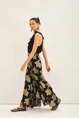 Pantalon de corte amplio y tiro alto, confeccionado en tejido jacquard negro con estampado floral en hilo metalizado dorado. Presenta una silueta fluida y holgada.