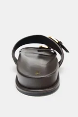 Sandalia plana de mujer color marrón oscuro, con dos tiras anchas de ante ajustables mediante hebillas metálicas doradas. Presenta una suela gruesa y plana.