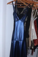 Vestido largo azul con corte bajo el busto, escote en V y top de lentejuelas. Presenta breteles finos cruzados en la espalda, recortes cut-out en la cintura y falda larga con tajo y volados.