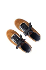 Championes urbanos de gamuza color marrón, con detalles en charol negro y bordes dorados. Presentan cordones negros y suela de goma al tono.
