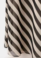 Vestido largo de fiesta con diseño de rayas diagonales en tonos beige y negro. Cuenta con tirantes finos, cuello drapeado y un adorno de fular incorporado en el cuello.