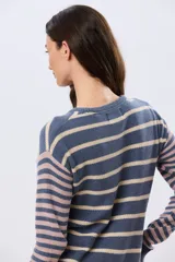 Buzo tejido de algodón con diseño a rayas horizontales, cuello redondo y mangas largas. El cuerpo presenta rayas en tonos azul y beige, mientras que las mangas combinan rayas en tonos azul y rosado.
