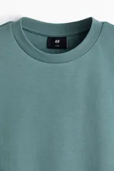 Remera de algodón color verde con cuello redondo ribeteado, mangas cortas y hombros caídos de corte holgado.