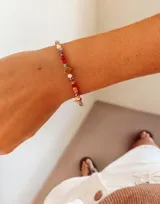 Pulsera elástica compuesta por pequeñas cuentas de cristal facetado en tonos cálidos y neutros, con un dije central cuadrado en tono dorado.