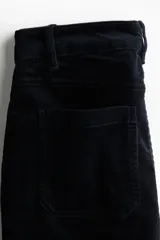 Pantalón acampanado de pana color negro, de tiro alto, con cierre de botón y bolsillos de parche delanteros y traseros.