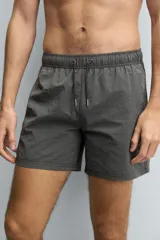 Bañador de hombre de largo medio, color celeste claro con rayas blancas horizontales. Presenta cintura elástica ajustable con cordón, bolsillos frontales y bolsillos traseros de plastrón. Incluye forro interior.