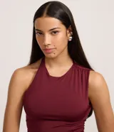 Vestido largo negro de microfibra, corte ajustado al cuerpo, con cuello redondo y escote tipo nadador en la espalda. Presenta una abertura lateral alta en la falda.