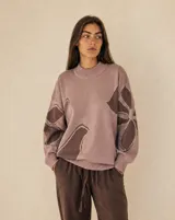 Buzo de punto amplio y relajado, color rosado con diseño floral en tonos marrones. Posee cuello redondo alto y terminaciones acanaladas en cuello, puños y ruedo.