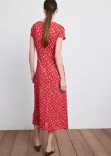 Vestido midi rojo con estampado floral blanco, cuello en V, manga corta y detalle de nudo frontal en el pecho.