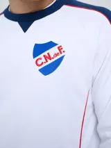 Buzo deportivo azul marino con detalles en rojo y blanco en cuello, hombros y mangas, de cuello redondo y manga larga, con el logo de Umbro y el escudo del Club Nacional de Football bordados en el pecho.