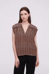 Blusa sin mangas de corte holgado, confeccionada en viscosa con estampado de rayas verticales en tonos negro, naranja y blanco. Presenta un escote en V profundo y detalles de bordado decorativo en los hombros.