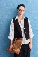 Chaleco negro con escote en V, cierre frontal con botones y bolsillos ribeteados simulados.