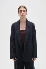 Blazer de corte holgado con diseño de rayas verticales, cuello solapa y cierre frontal con un botón. Cuenta con bolsillos laterales con solapa.