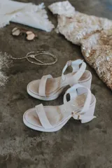 Sandalias de tacón alto de gamuza color beige, con tira delantera, plataforma y tira ajustable al tobillo con hebilla metálica.