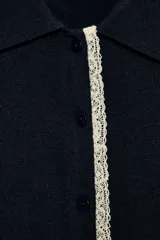 Chaqueta de manga corta y punto en color beige, con cuello polo y cierre frontal de botones. Presenta detalles de puntilla a contraste en la botonera y los puños.