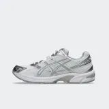 Championes Asics modelo Gel 1130, color blanco con detalles plateados y verde oscuro. Diseño retro inspirando en el running con tecnología GEL en el talón.