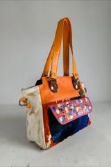 Cartera de cuero multicolor de diseño artesanal e intervenida con arte, modelo Lira de la Línea Dubai, con doble asa de hombro y bolsillo frontal con solapa pintada.