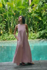 Vestido midi de corte fluido, cuello redondo y diseño sin mangas. Presenta una abertura en la espalda con cierre de lazada ajustable.