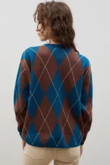 Buzo de punto con diseño de rombos en tonos azul y marrón, con cuello redondo y mangas largas.