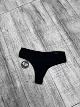 Bombacha de bikini tiro alto de color negro, con diseño clásico y detalle de placa metálica con logo en el lateral.