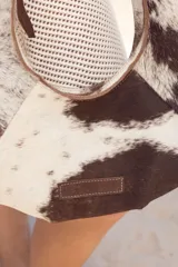 Cartera negra de cuero con forma de medialuna y tachas en zigzag.