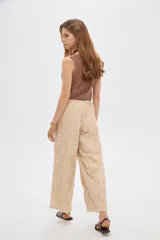 Pantalón ancho de poliéster color beige con diseño bordado floral en hilo blanco, cintura elastizada con cordón ajustable.