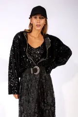 Campera de lentejuelas negras, con cierre frontal, cuello camisero y mangas largas holgadas.