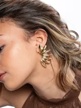Aros tipo ear cuff dorados con diseño en abanico compuesto por piezas metálicas alargadas y tridimensionales similares a pétalos.