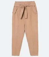 Pantalón cargo de tiro medio color beige, con cintura alta fija, cinturón ajustable para anudar, bolsillos laterales con solapa y botones, recortes verticales en las piernas y cierre frontal con botón y cremallera.