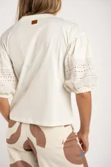 Remera negra de algodón con mangas tres cuartos abullonadas y detalle de bordado calado tipo ojal en la zona del antebrazo.