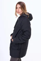 Campera acolchada de corte largo, color negro, con cierre frontal, capucha ajustable con cordones y bolsillos frontales tipo cargo.