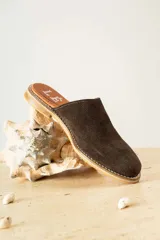 Mules de cuero negro con tachas plateadas en el borde de la suela y plantilla con logo estampado.