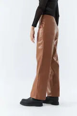 Pantalón marrón de cuero sintético, tiro medio, corte recto cropped y detalle de costuras verticales.