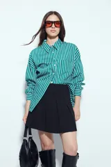 Minifalda tableada de color negro, con diseño de tablas anchas que aportan volumen y movimiento. Presenta un corte estructurado y un calce cómodo.