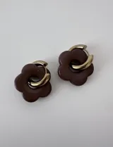 Aros de acero quirúrgico con argolla dorada y dije colgante en forma de flor color marrón.