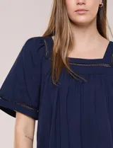Blusa de corte holgado color marfil, confeccionada en mezcla de modal y algodón, con escote cuadrado y mangas cortas adornadas con detalles de puntilla calada.