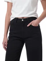 Jeans de denim negro de tiro alto y pierna ancha, con diseño clásico de cinco bolsillos, cierre de cremallera y botón metálico.