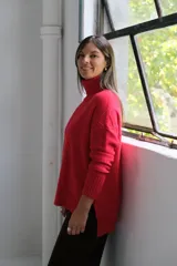 Polerón de punto color rojo con cuello alto y diseño de rombos texturizados. Presenta mangas largas con puños acanalados y un corte holgado con ruedo asimétrico.