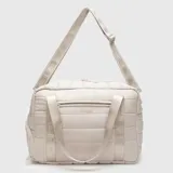 Bolso deportivo tipo duffel de diseño acolchado en color beige. Cuenta con compartimento lateral independiente para calzado, cierre superior con cremallera, bolsillo frontal con cierre, asas de mano y correa ajustable para el hombro con logo de la marca.