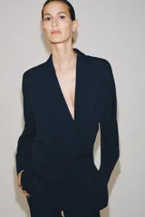 Blazer de corte fluido confeccionada en mezcla de viscosa, con cuello solapa, manga larga con puños abotonados y cierre frontal cruzado con botón único.